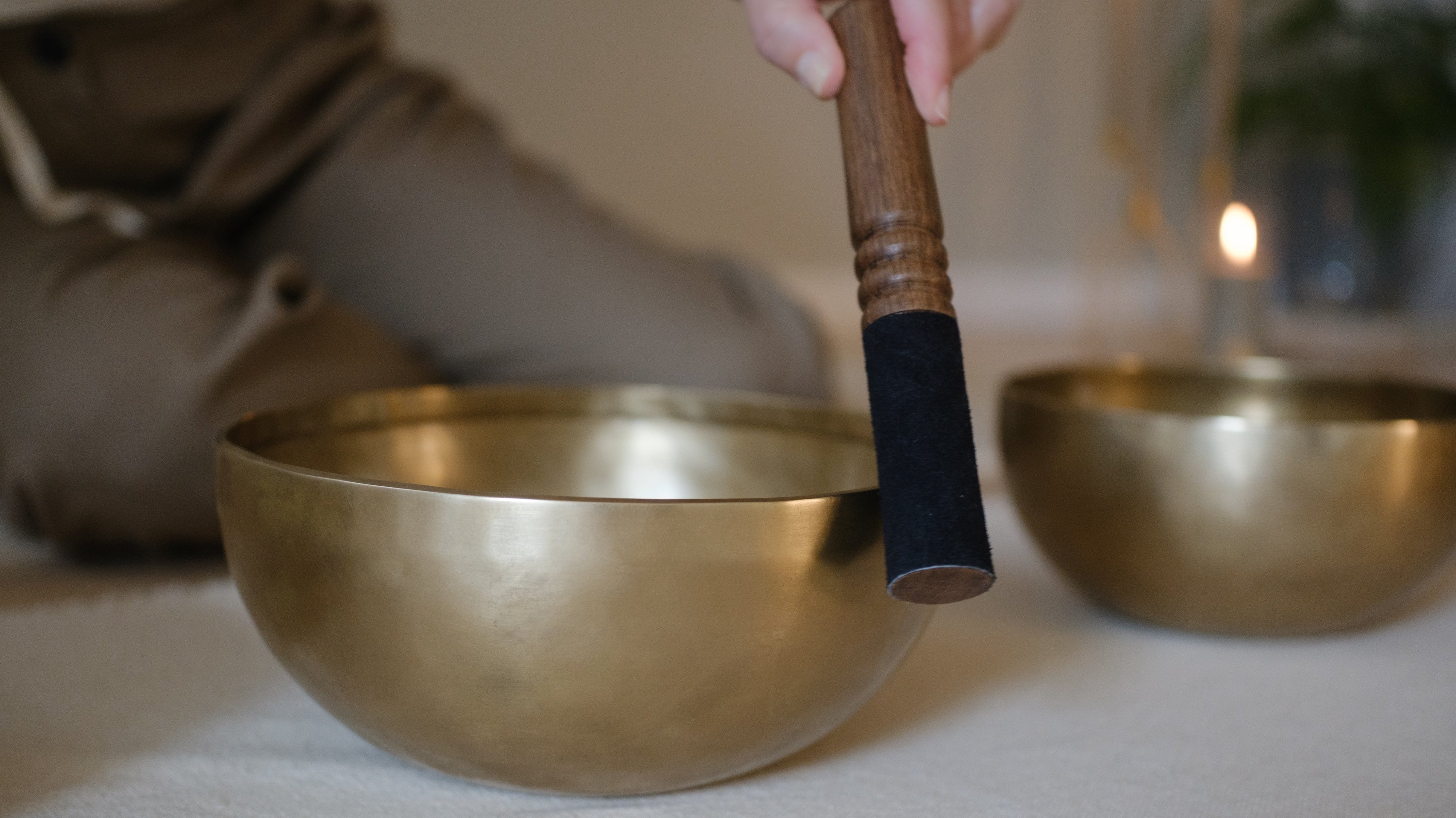 A woman striking a singing bowl with a mallet