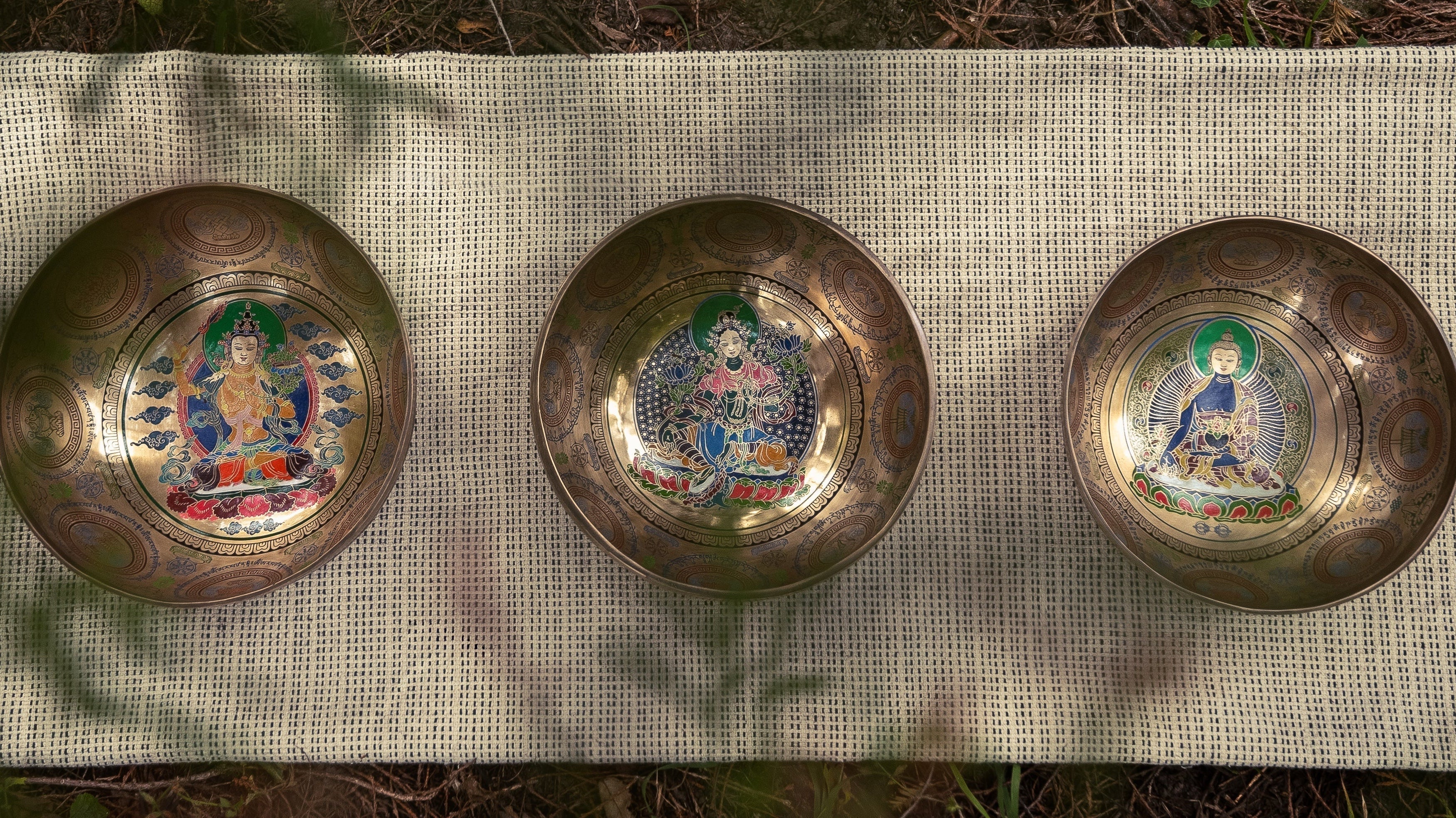 Three Etched Singing Bowls resting on the ground in the nature