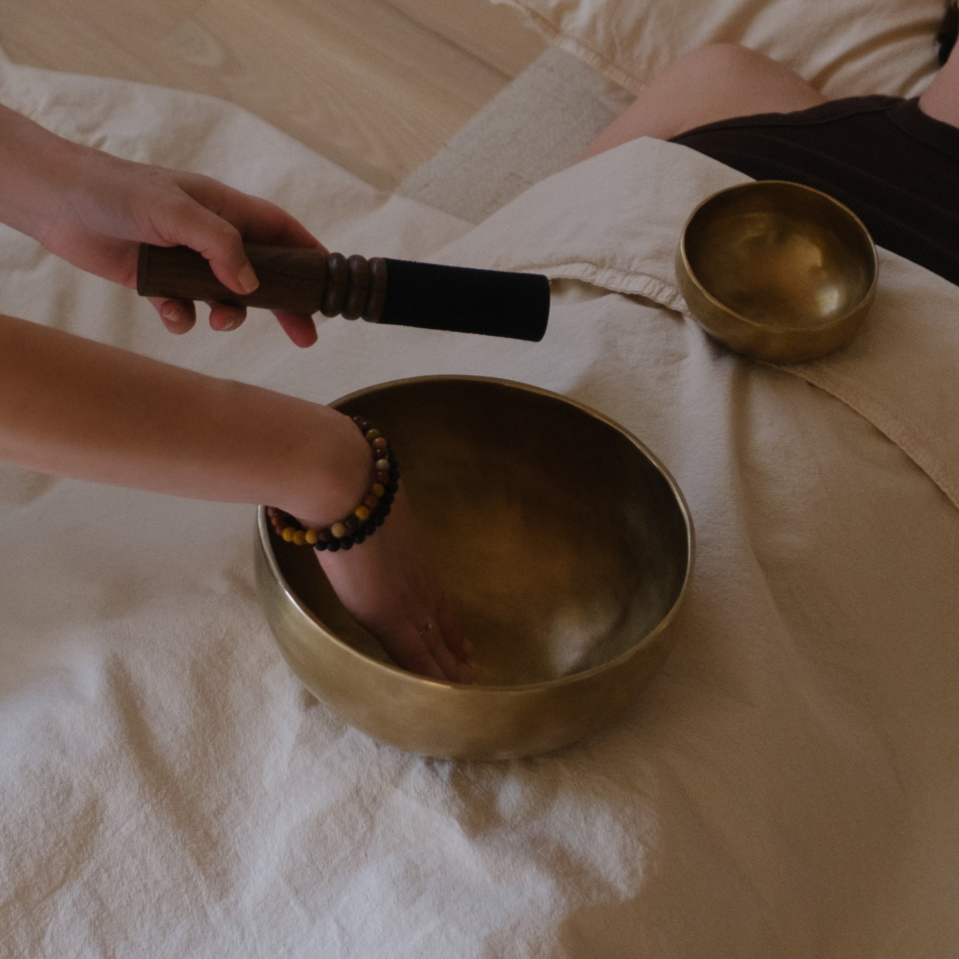 Sound healer providing sound healing to another woman with dim singing bowls