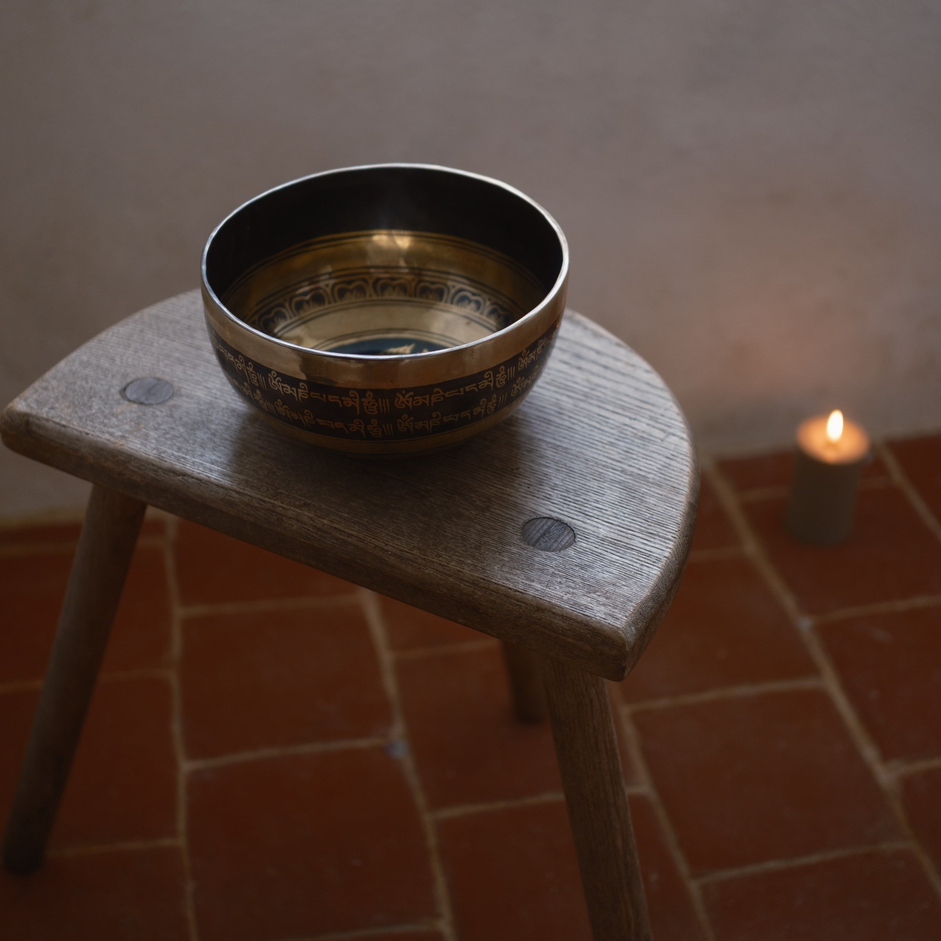 Singing bowl on a wooden stool with a candle in the background