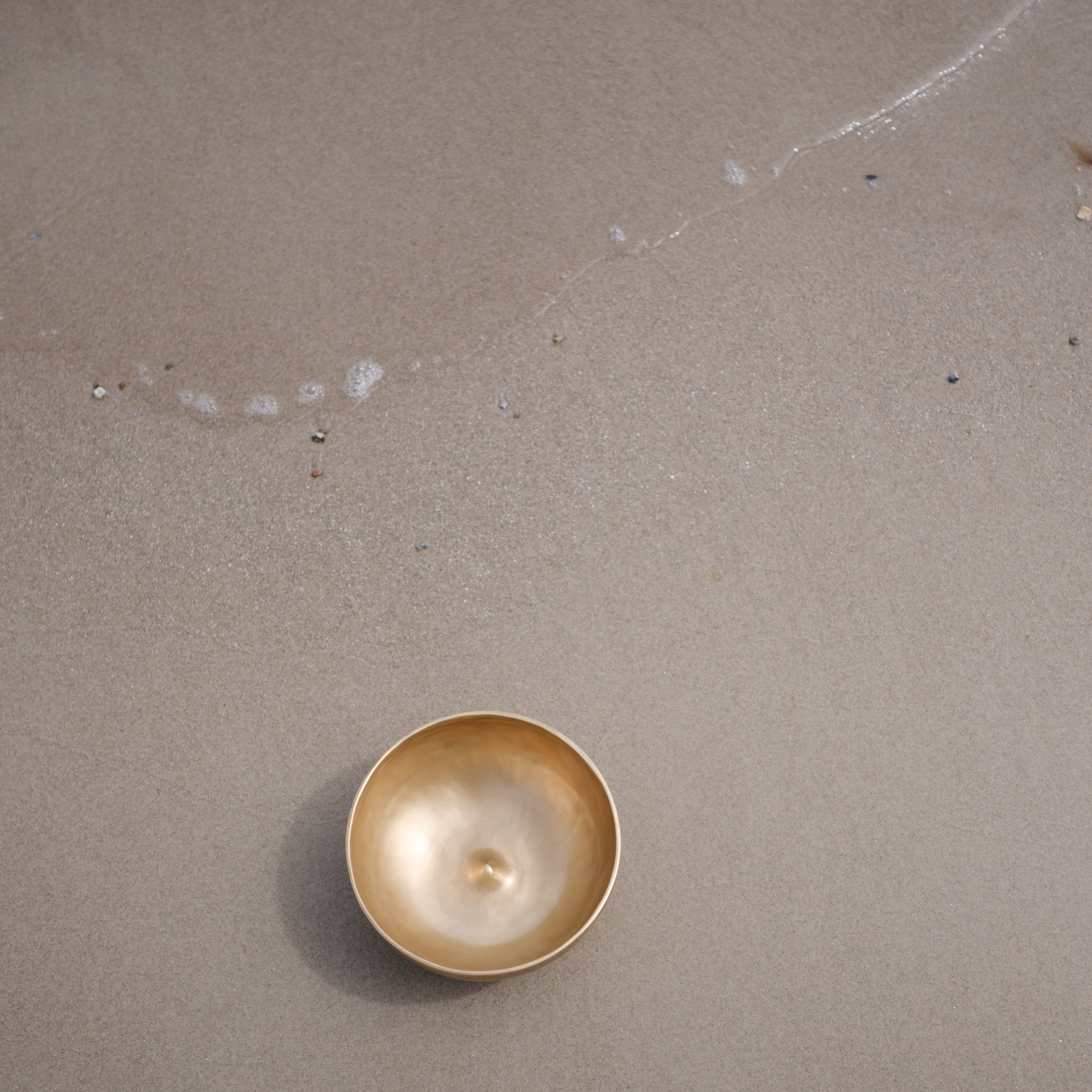 Lingam Singing bowl on a sandy surface