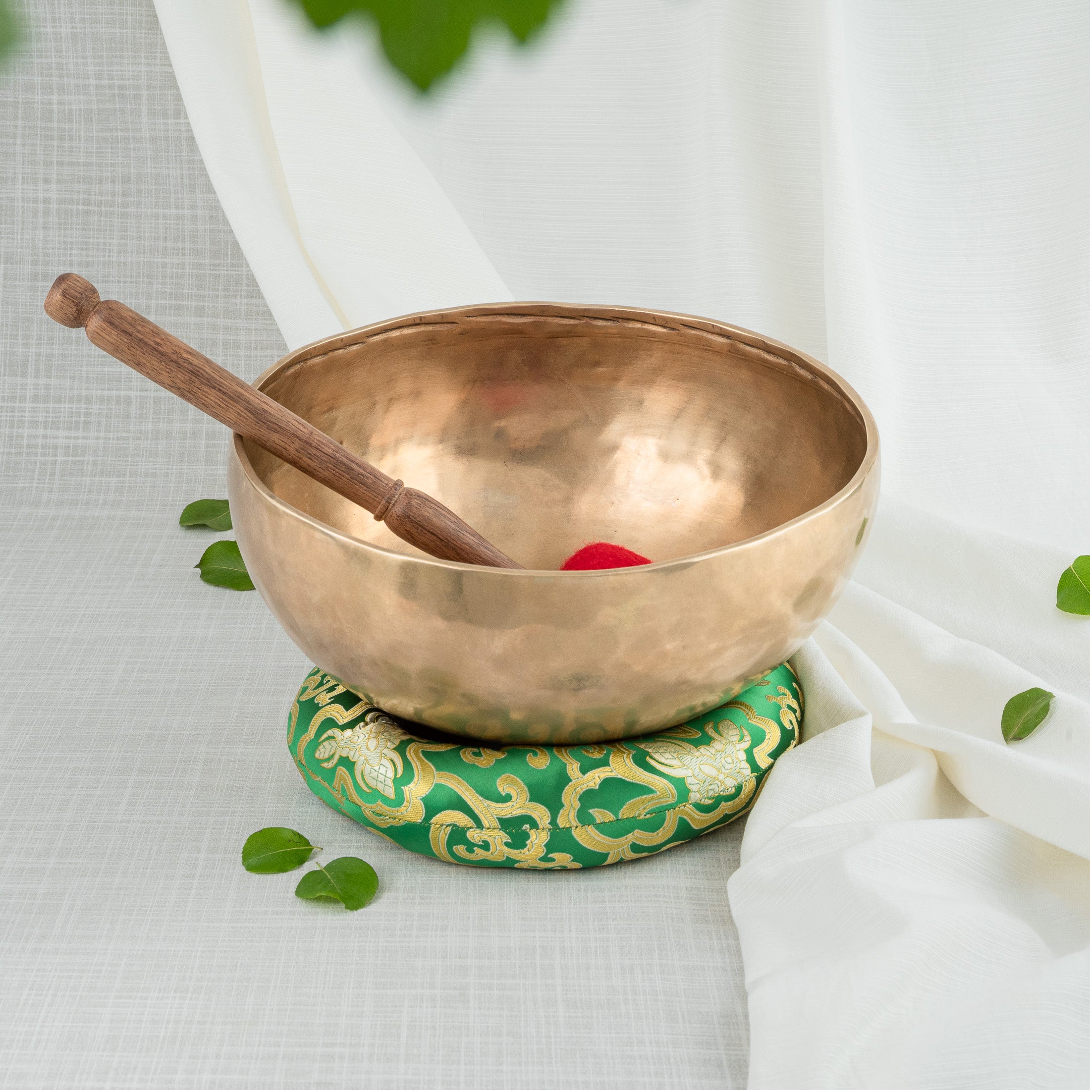 Bronze singing bowl, mallet and green cushion