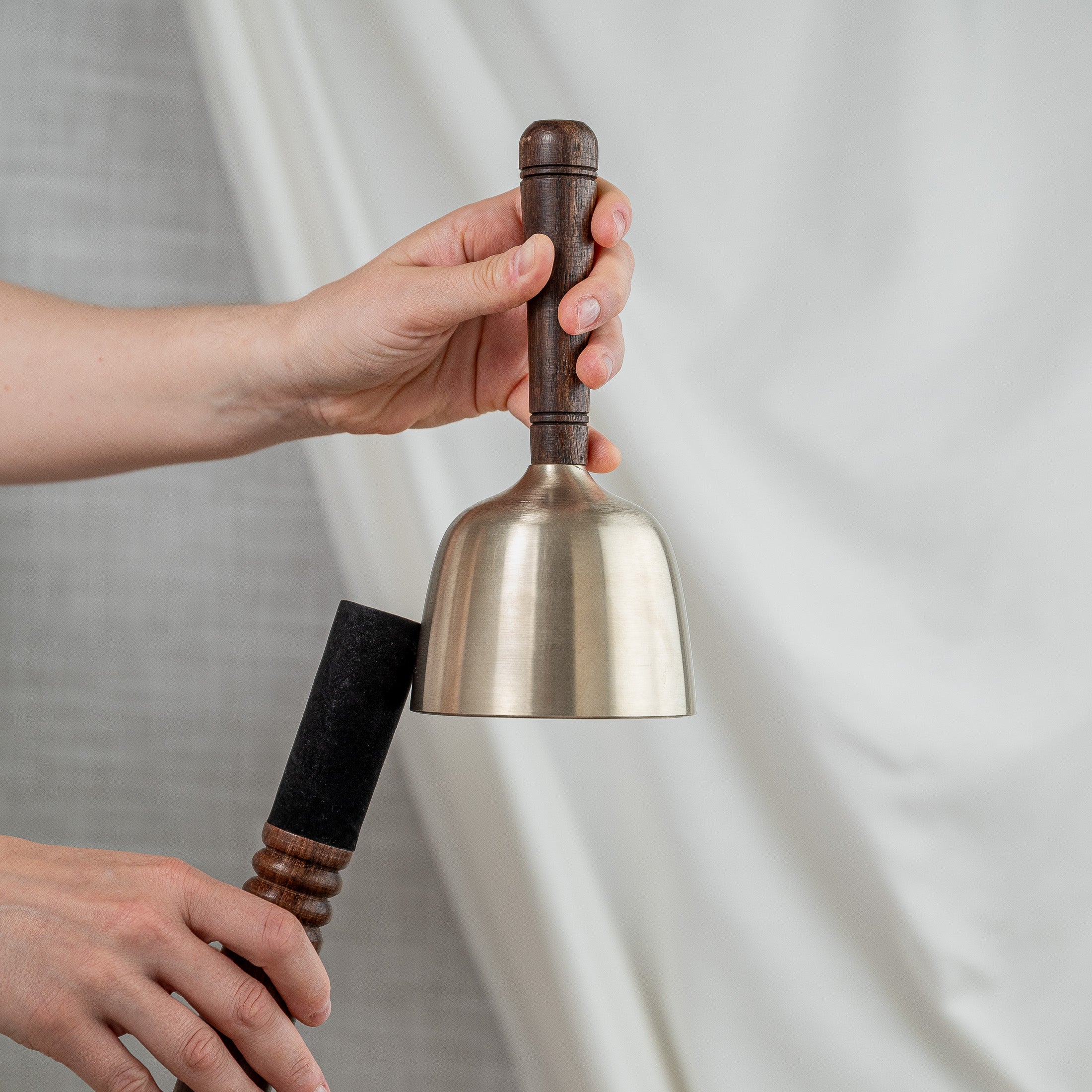 Person holding singing bowl with wooden handle