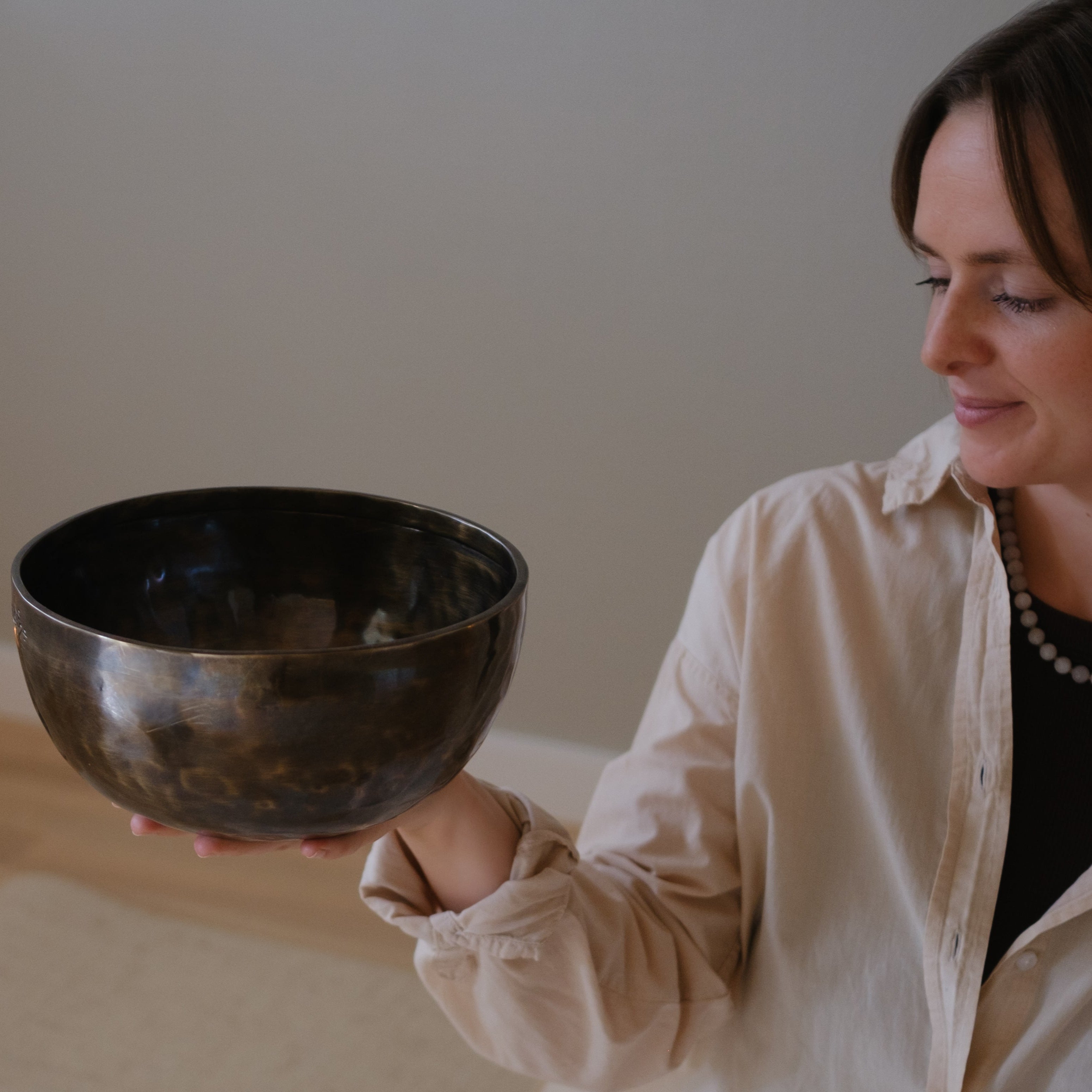 Woman holding a large lunar energy singing bowl against a neutral background
