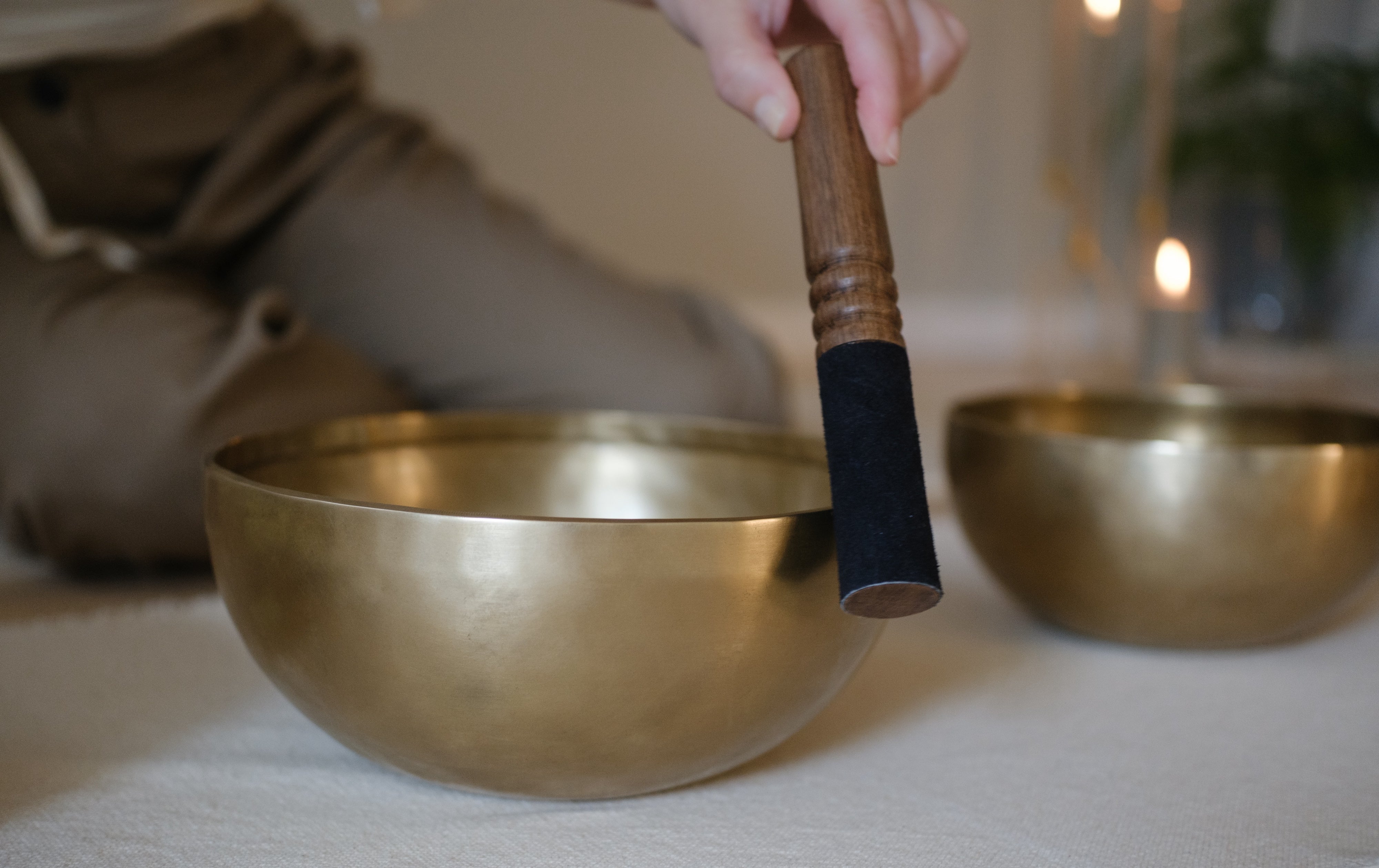 A woman striking a singing bowl with a mallet