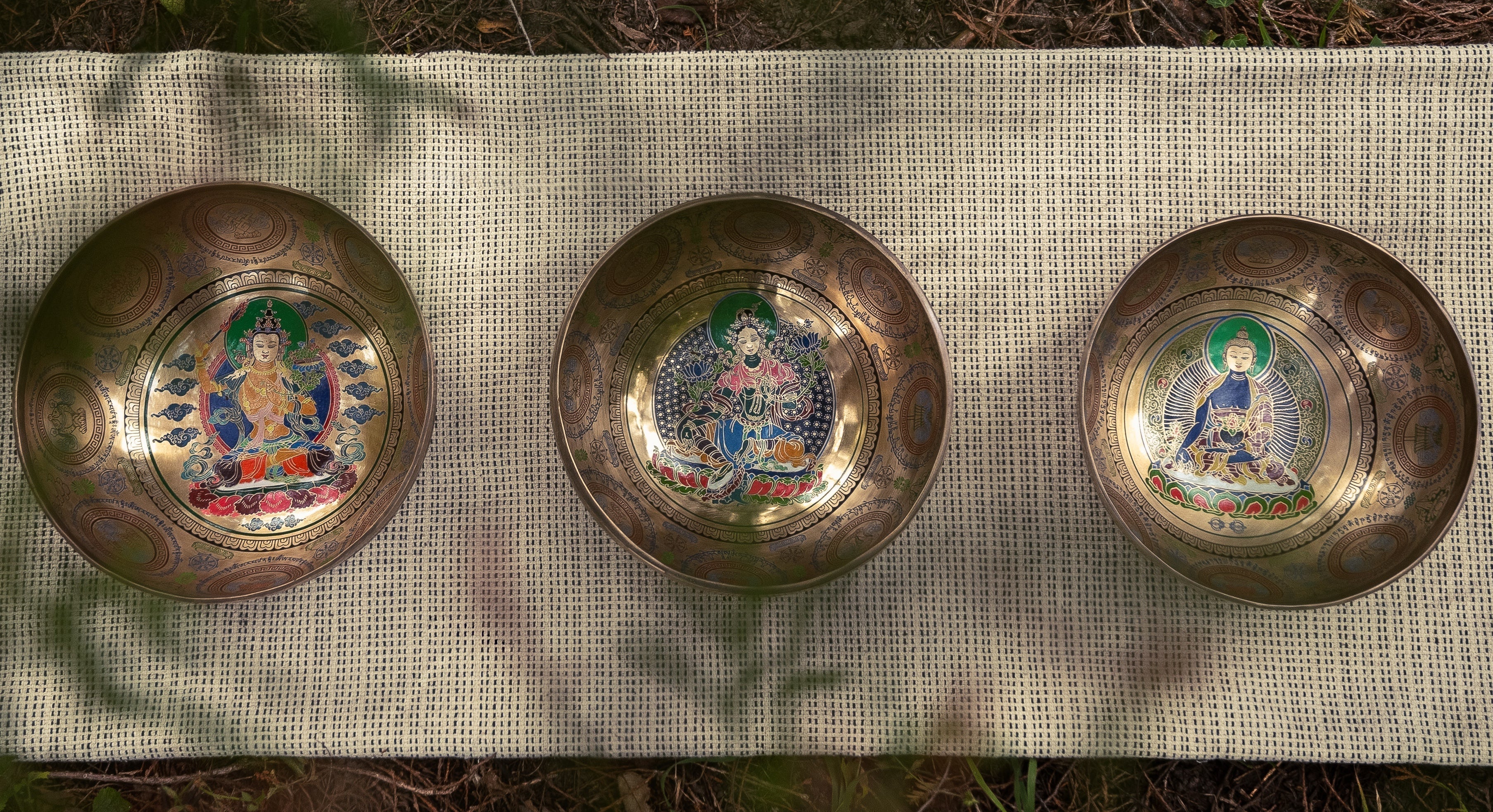 Three Etched Singing Bowls resting on the ground in the nature