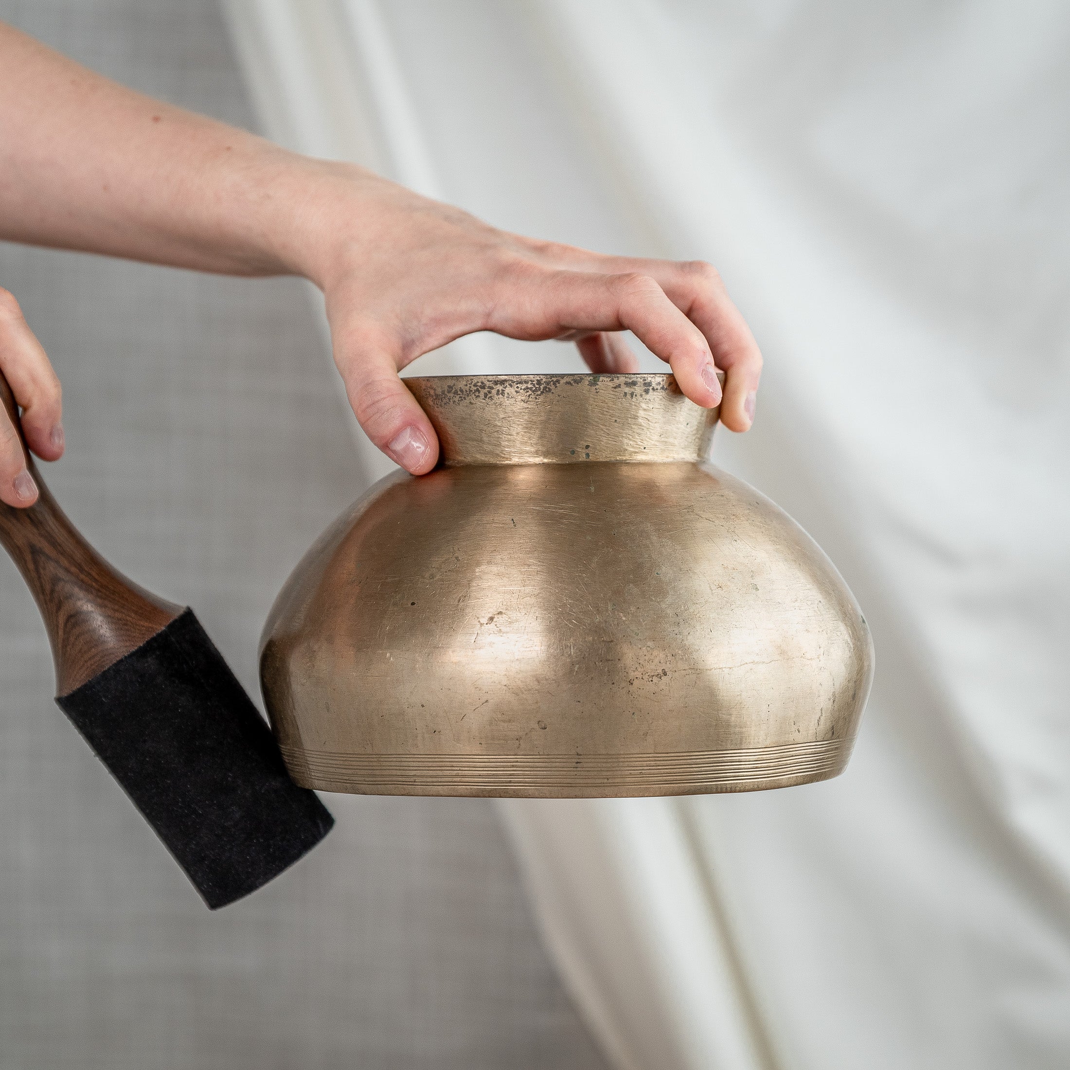 Person holding antique pedestal singing bowl downwards