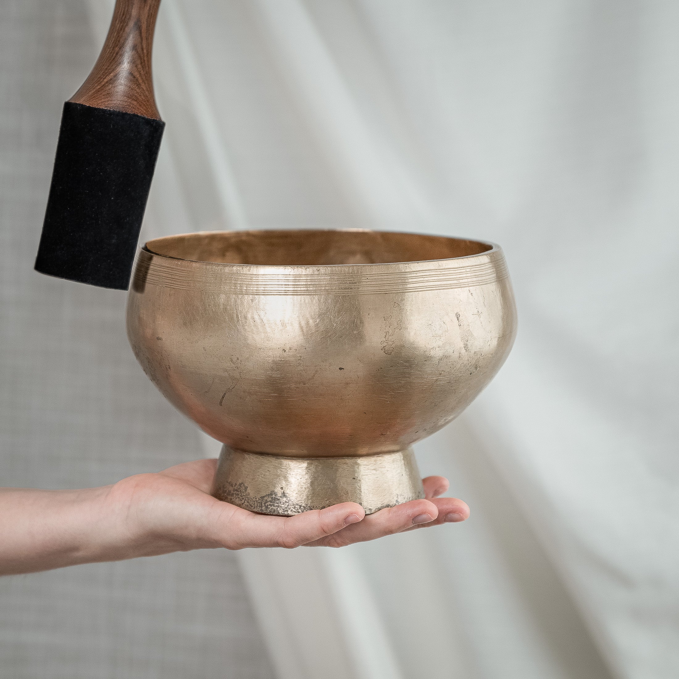 Person holding antique pedestal singing bowl