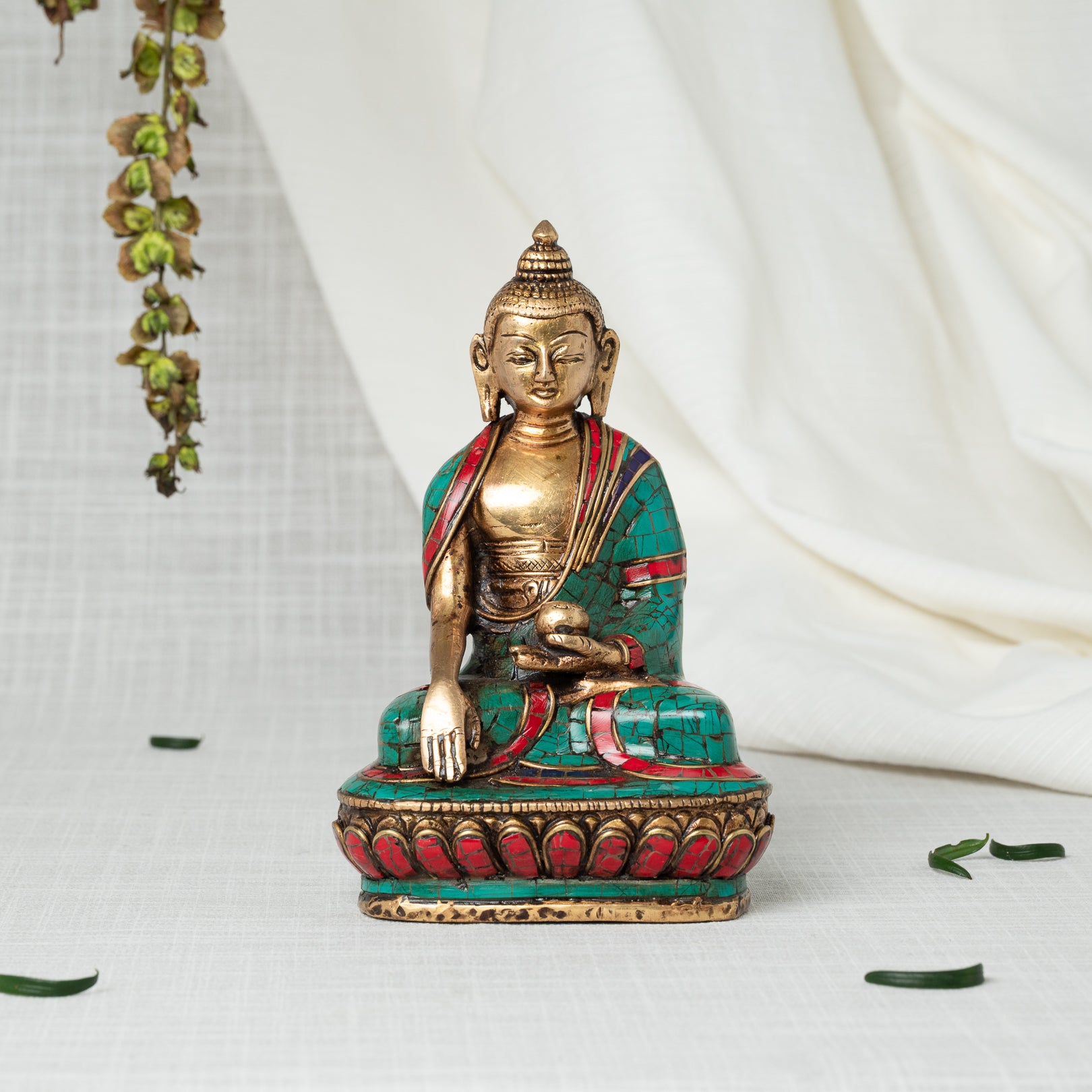 Decorative statue of a Buddha statues with gold, green, and red colors on a white background.