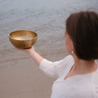 Person med en lingam-klangskål på en strand