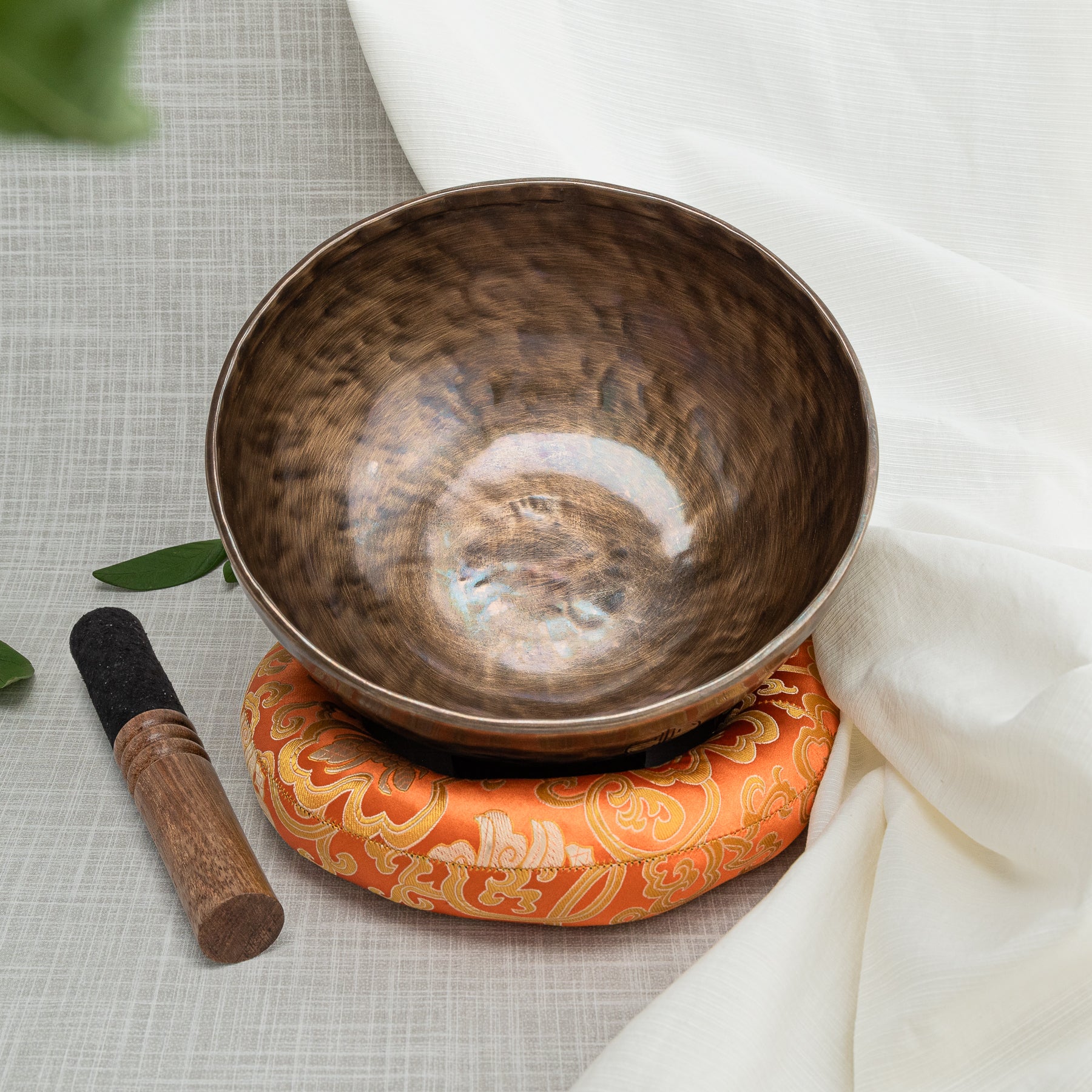 Singing bowl with mallet and orange pillow