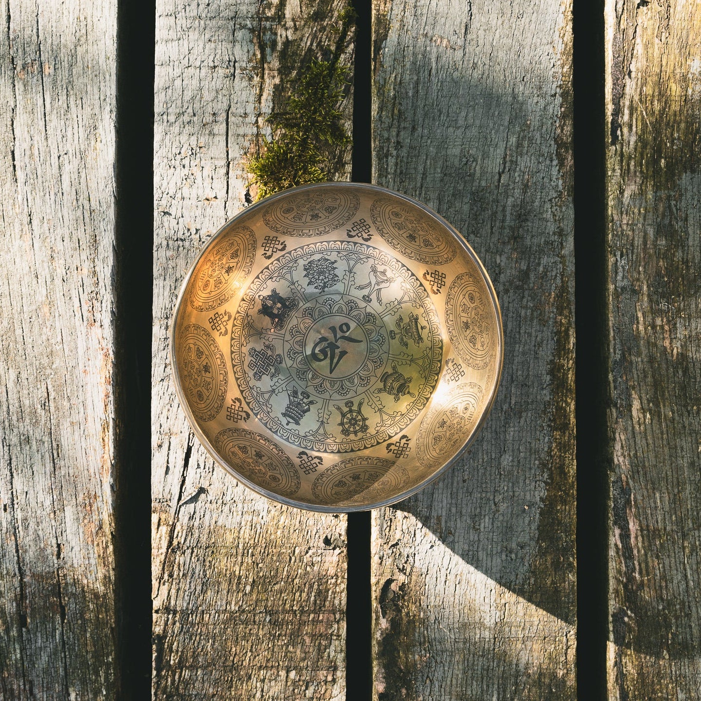 Eteched singing bowl intricate patterns on a wooden surface