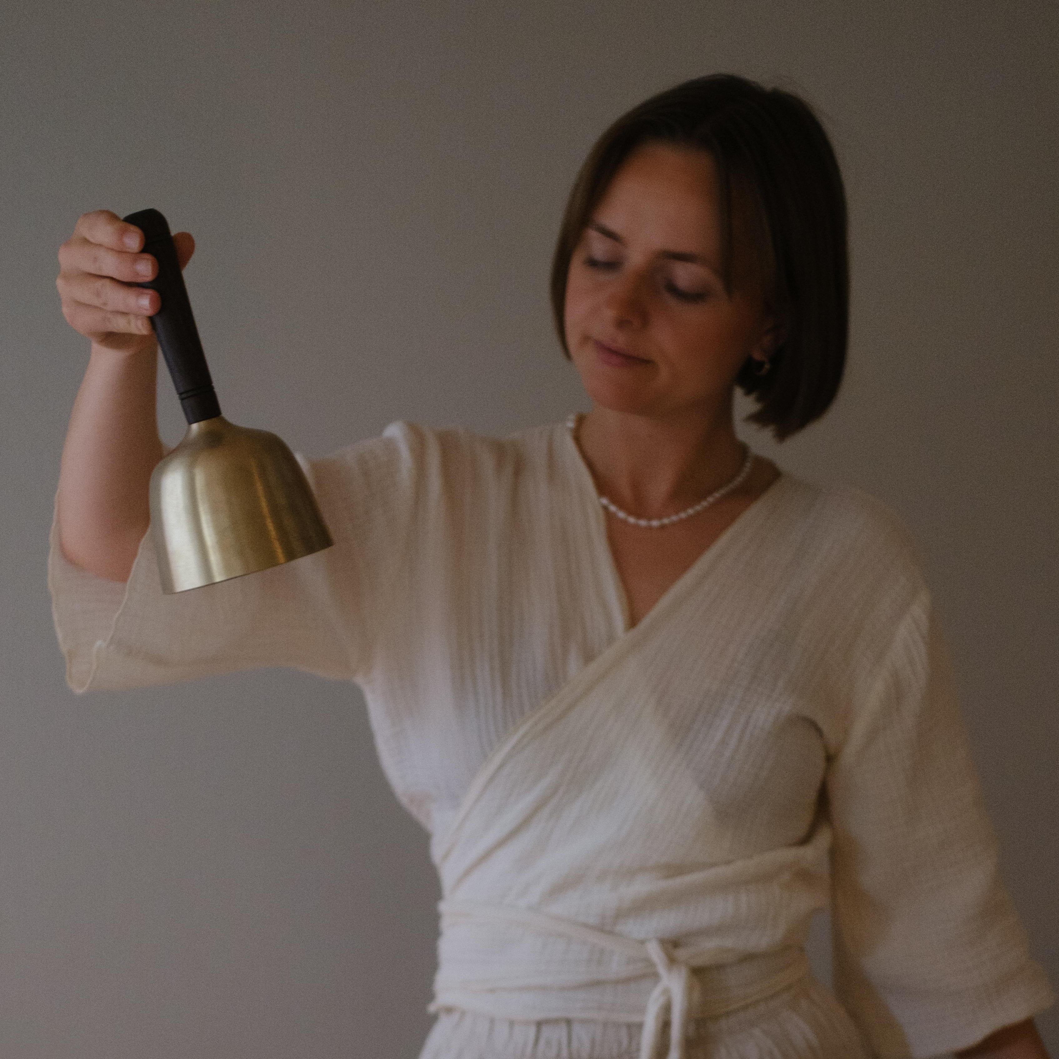 Model holding singing bowl with wooden handle